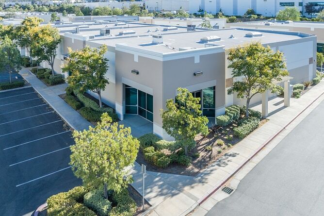 Aerial view of commercial storefronts with trees and shrubbery