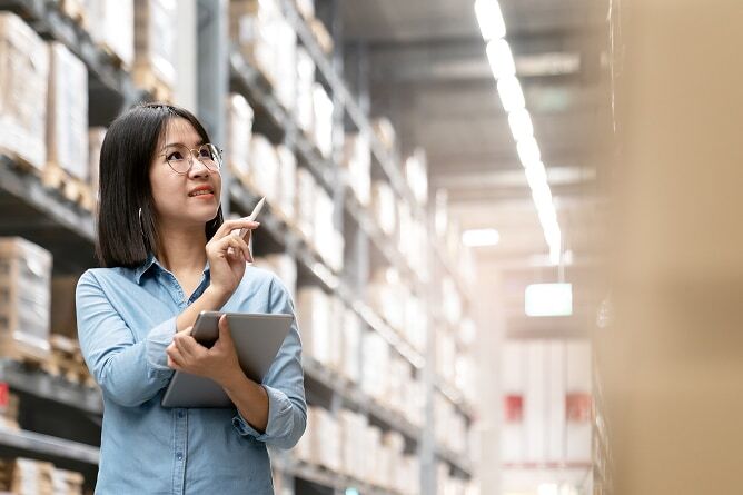 Woman taking inventory in warehouse aisle