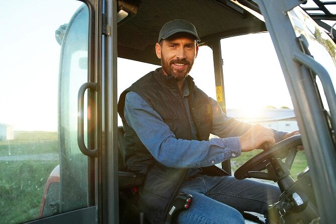 Farmer sitting in cabin of a large tractor with field in background