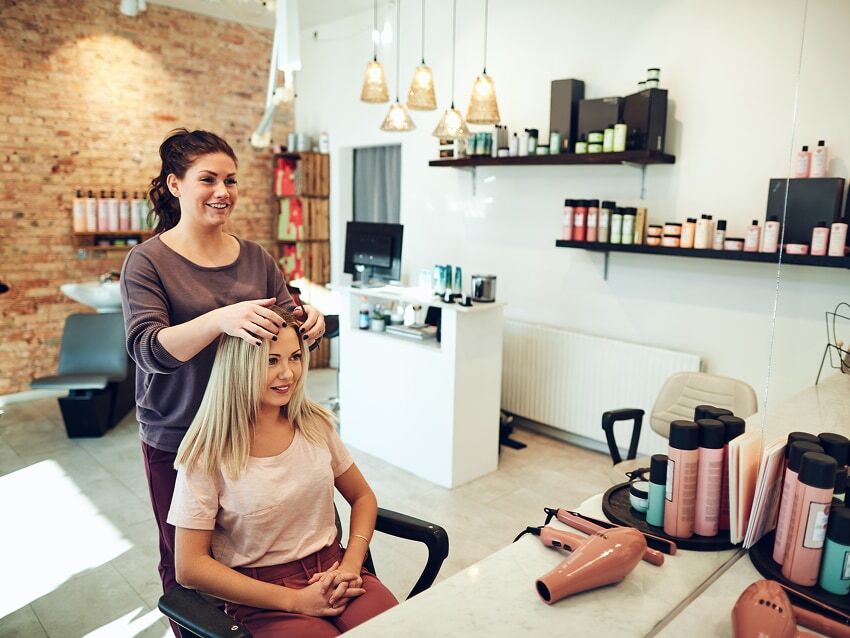 Hairstylist standing behind female client working on hair in a salon