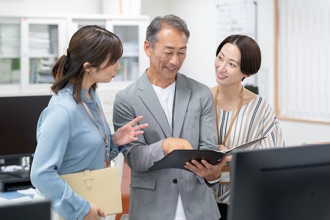 Employer and two employees looking at reports on a tablet computer
