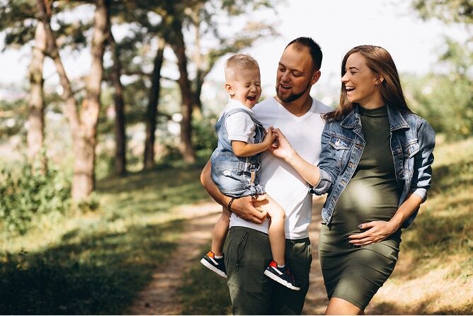Husband, pregnant wife and toddler son walking outdoors