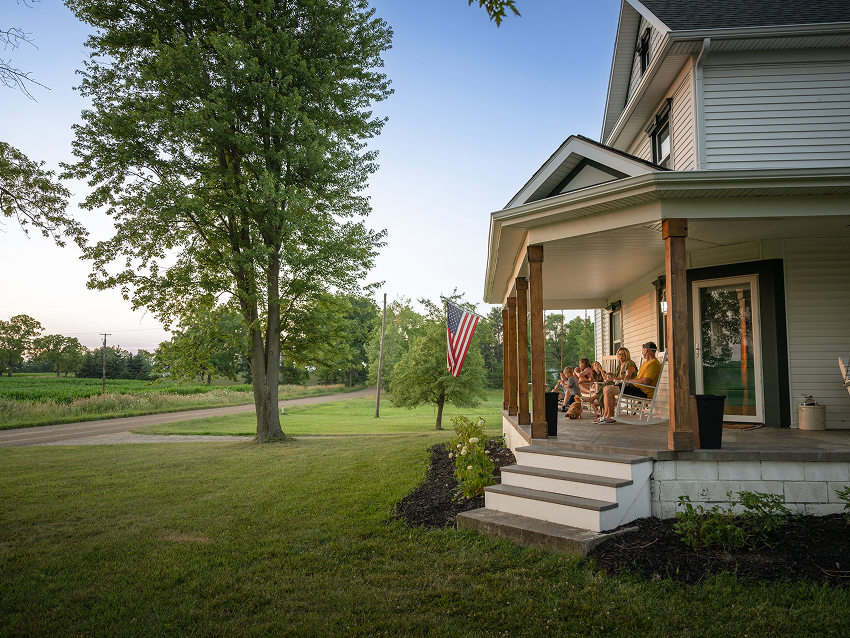 Family sitting on front porch with tree in front yard