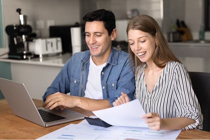 Young couple sitting at dining room table reviewing finances