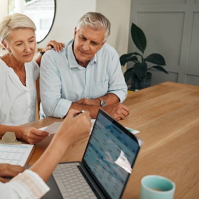 Mature couple meeting at table with advisor and looking at financial reports