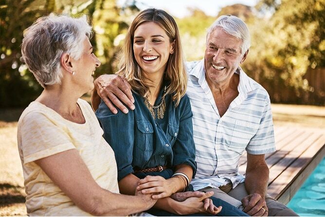 Young woman sitting with parents by pool