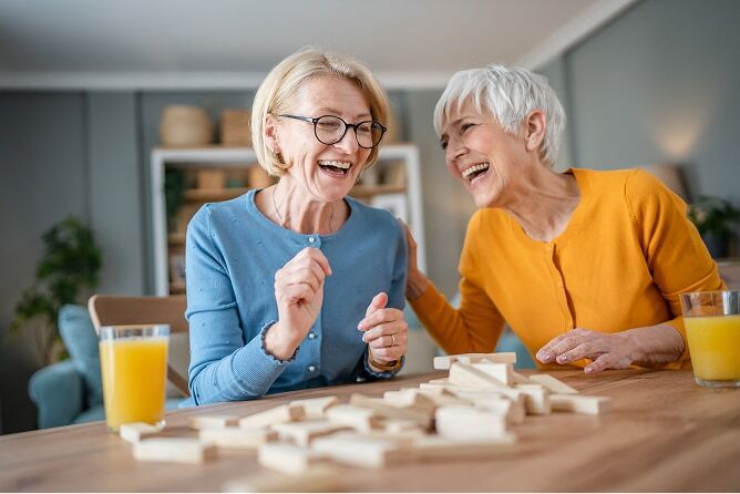 Two mature women playing dominoes and laughing