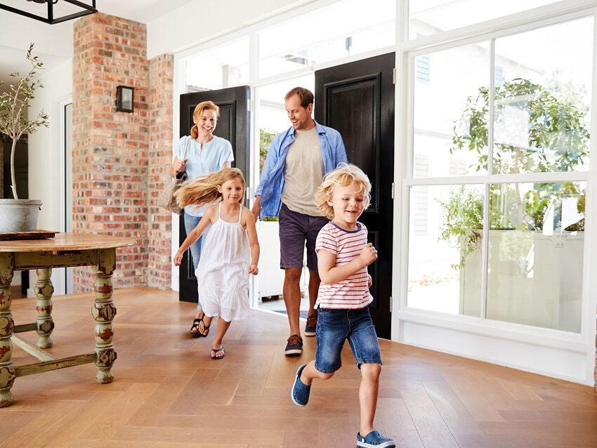 Two young children running into house with parents following