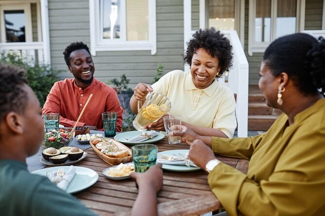 Woman pouring drink for family member at outdoor dining table