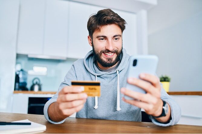 Man shopping online on his phone and holding credit card