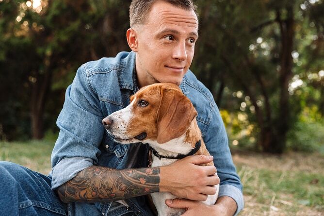 Man hugging dog at a park