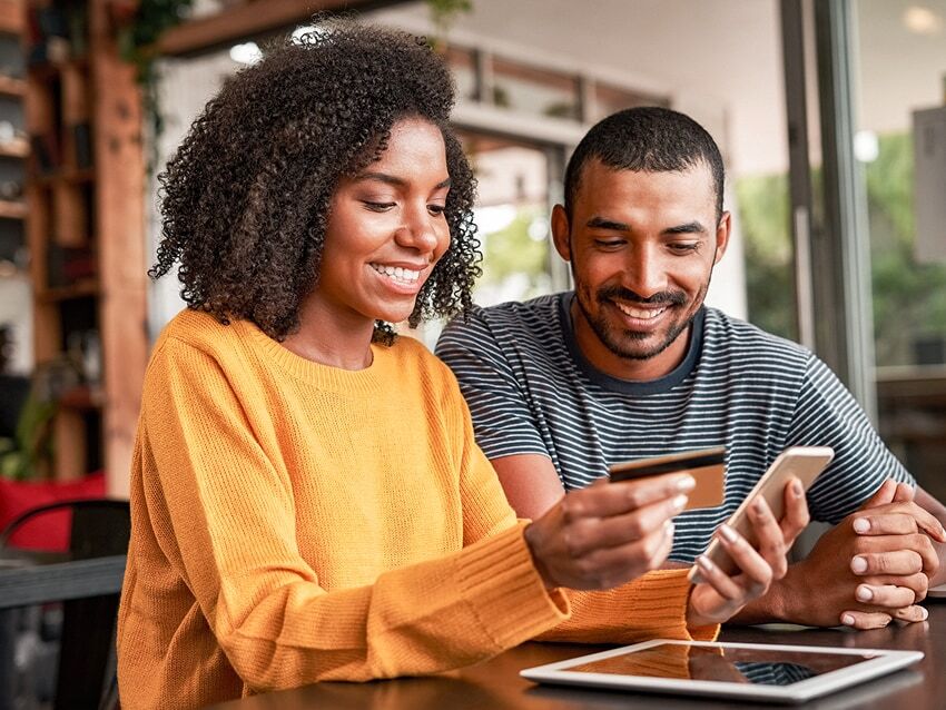 Couple making online purchase on a phone in a cafe