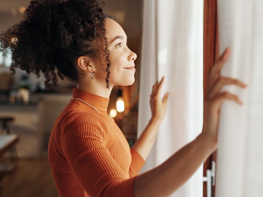 Woman smiling in front of window inside house