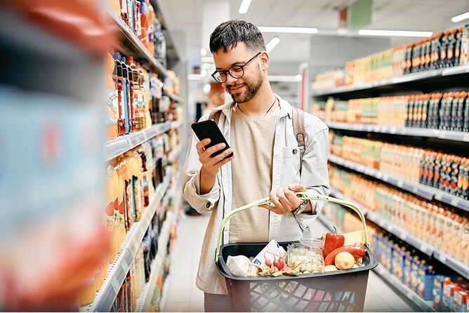 Young man looking at phone in grocery store aisle