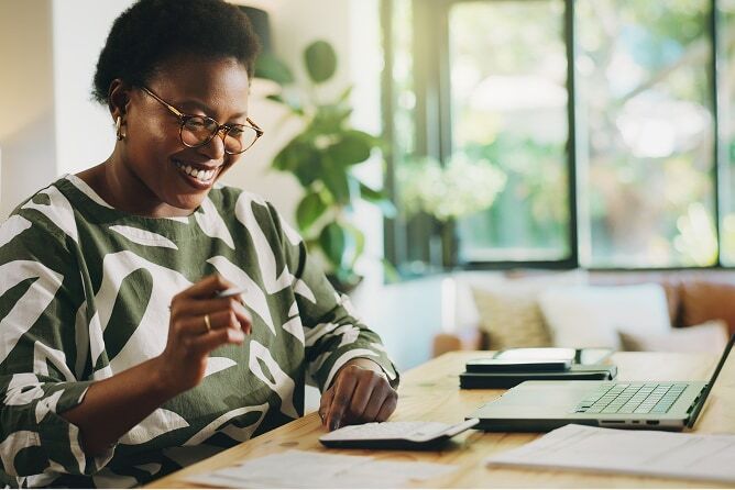  Lady checking finances with laptop, calculator and papers sitting on table