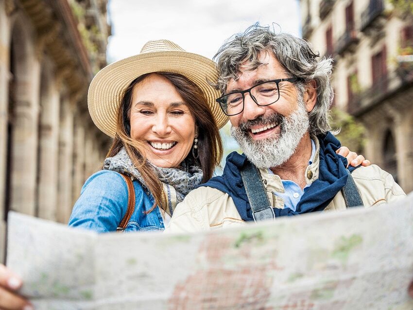 Husband and wife looking at map with historic buildings in the background