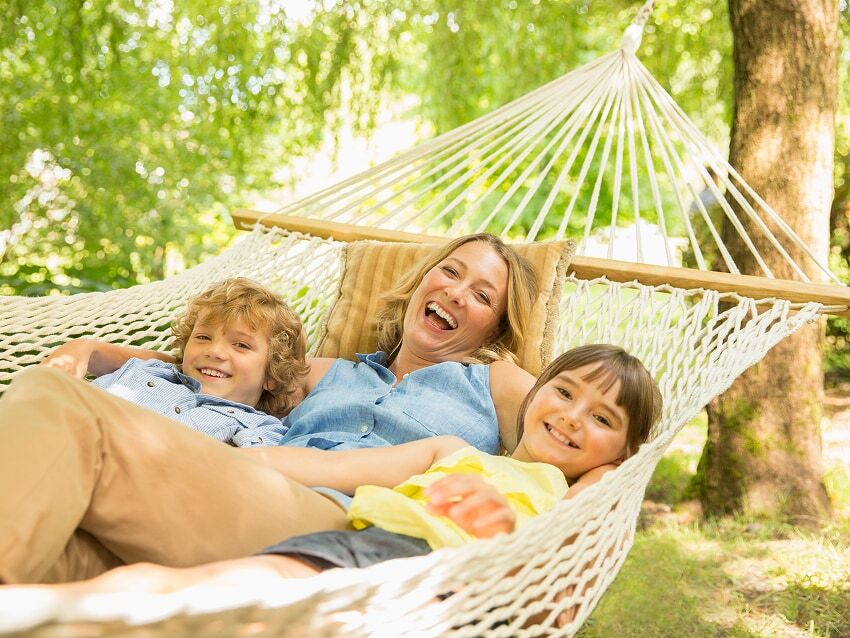 Mother and two young children swinging in hammock