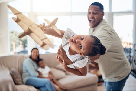 a father playing with his daughter and a toy airplane