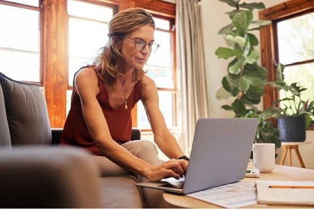 Woman sitting on living room couch typing on computer