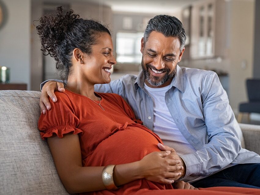 Picture of a husband smiling down at pregnant wife in living room