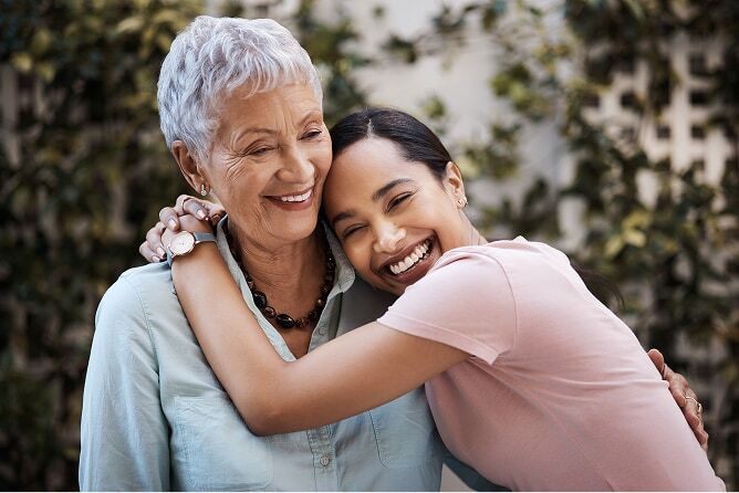 Photo of a daughter hugging her mother, both laughing