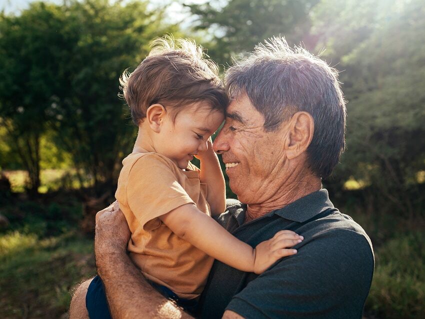 Grandfather holding infant grandchild with their foreheads together