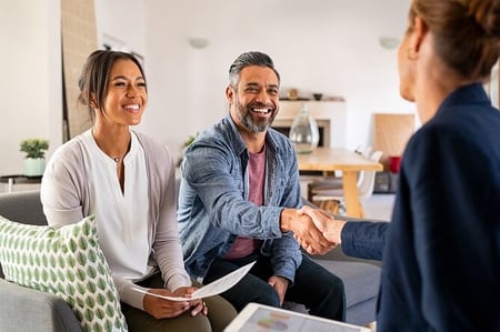 Young couple sitting on couch and man shaking hands with advisor