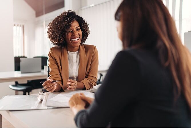 Female financial advisor showing woman a portfolio of paperwork in an office