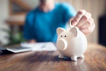 Person dropping coins into ceramic piggy bank